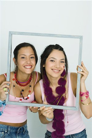 simsearch:696-03394582,k - Two young friends holding up frame together, smiling at camera, portrait Foto de stock - Royalty Free Premium, Número: 695-05766844