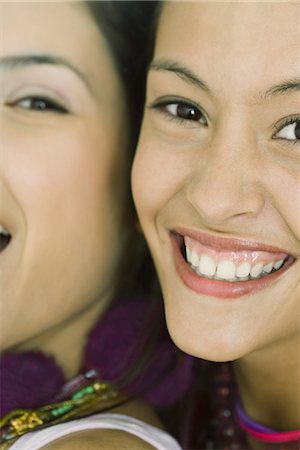 Two young friends smiling at camera together, cheek to cheek, cropped view Stock Photo - Premium Royalty-Free, Code: 695-05766849