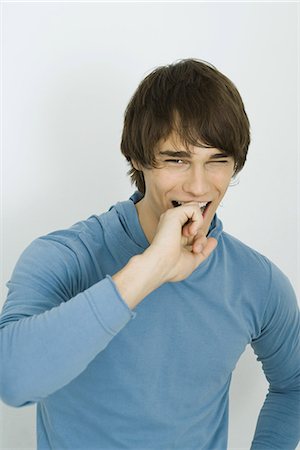 Young man smiling at camera, covering mouth with hand Foto de stock - Sin royalties Premium, Código: 695-05766860