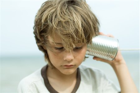 Boy listening to tin can phone, looking down, portrait Foto de stock - Royalty Free Premium, Número: 695-05767053