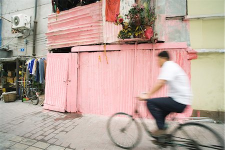 side view of a guy riding a bike - China, Guangdong Province, Guangzhou, man riding bicycle through street Stock Photo - Premium Royalty-Free, Code: 695-05767127