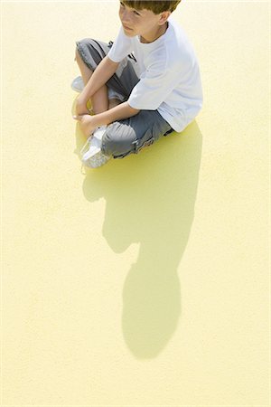 patient shadow - Boy sitting indian style on the ground, high angle view Stock Photo - Premium Royalty-Free, Code: 695-05767208