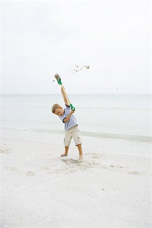 simsearch:695-03377206,k - Young boy at the beach holding up shovel, throwing sand Foto de stock - Sin royalties Premium, Código: 695-05767240
