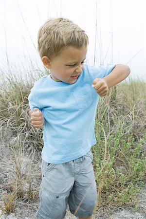 simsearch:695-03389917,k - Young boy holding up elbow, wrinkling nose Foto de stock - Royalty Free Premium, Número: 695-05767256