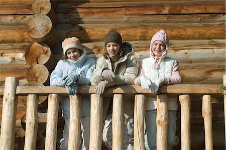 Three preteen or teen girls standing on deck of log cabin, looking away, low angle view Stock Photo - Premium Royalty-Free, Code: 695-05767278
