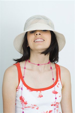 simsearch:695-05766280,k - Teenage girl looking at camera from beneath hat, smiling, portrait Stock Photo - Premium Royalty-Free, Code: 695-05767284