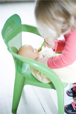 Blonde toddler girl pretending to feed baby doll Stock Photo - Premium Royalty-Free, Code: 695-05767363