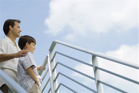 family in balcony - Father and son standing by railing looking at sky, low angle view Stock Photo - Premium Royalty-Free, Code: 695-05767408