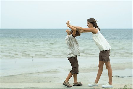 Brother and sister standing face to face at the beach with clasped hands Stock Photo - Premium Royalty-Free, Code: 695-05767424