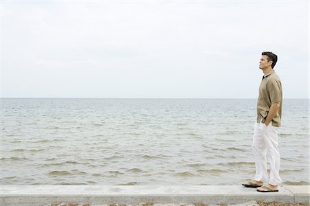 L'homme se tenant debout sur le muret de l'océan, mains dans les poches, pleine longueur Photographie de stock - Premium Libres de Droits, Code: 695-05767463