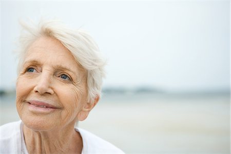 senior woman hope - Senior woman smiling, looking up, beach in background Stock Photo - Premium Royalty-Free, Code: 695-05767470