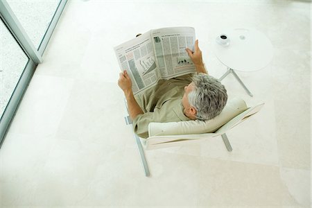 Man sitting, reading newspaper, high angle view Foto de stock - Sin royalties Premium, Código: 695-05767523