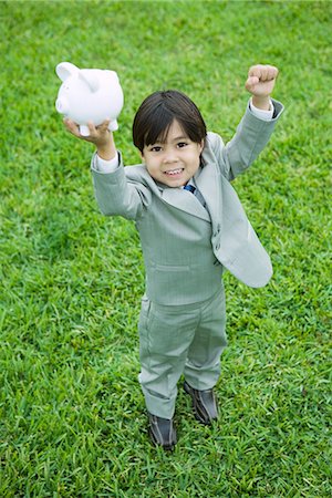 simsearch:640-05760828,k - Little boy dressed in full suit holding up piggy bank Stock Photo - Premium Royalty-Free, Code: 695-05767537