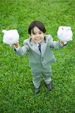 simsearch:640-05760828,k - Little boy dressed in full suit holding up piggy banks Stock Photo - Premium Royalty-Free, Code: 695-05767538