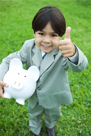 simsearch:640-05760828,k - Little boy dressed in full suit holding piggy bank, giving thumbs up signal to camera, smiling Stock Photo - Premium Royalty-Free, Code: 695-05767540