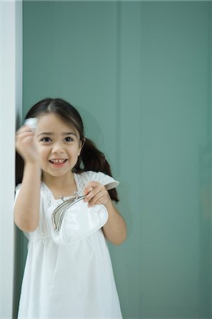simsearch:695-05767597,k - Little girl holding coin purse, one hand raised, smiling Fotografie stock - Premium Royalty-Free, Codice: 695-05767597
