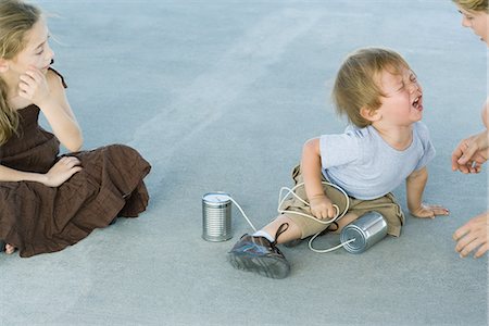 Little boy holding tin can phone, having tantrum, mother and sister watching Foto de stock - Royalty Free Premium, Número: 695-05767599