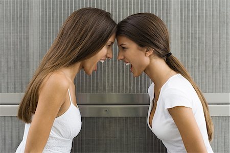 Teenage twin sisters leaning with foreheads touching, both shouting, side view Stock Photo - Premium Royalty-Free, Code: 695-05767604