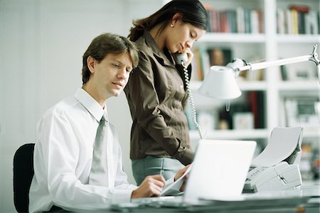 fax - Male and female colleagues at desk, man using laptop computer, woman using phone Fotografie stock - Premium Royalty-Free, Codice: 695-05767649