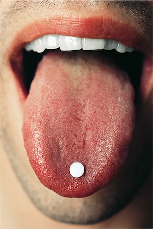 showing his teeth - Man holding pill on tongue, extreme close-up Stock Photo - Premium Royalty-Free, Code: 695-05767738