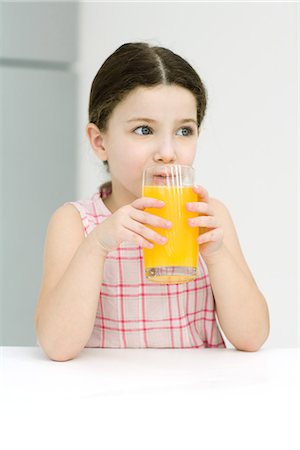 Little girl drinking orange juice, looking away, close-up Stock Photo - Premium Royalty-Free, Code: 695-05767765