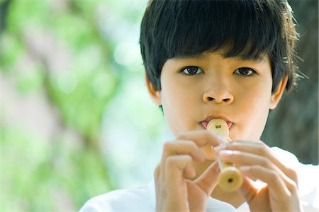 Boy playing flute outdoors, looking at camera Stock Photo - Premium Royalty-Free, Code: 695-05767826