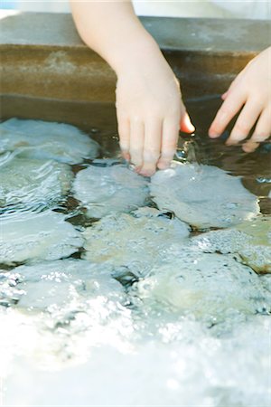 Child touching rocks in shallow pool, cropped view Stock Photo - Premium Royalty-Free, Code: 695-05767828