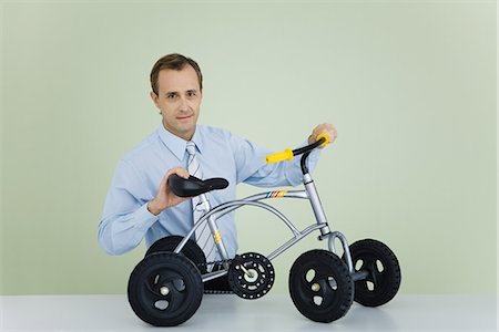 simsearch:695-05779541,k - Man holding child's bicycle, looking at camera Stock Photo - Premium Royalty-Free, Code: 695-05767874