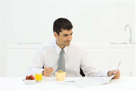 simsearch:400-06871178,k - Man having breakfast in kitchen and reading newspaper Stock Photo - Premium Royalty-Free, Code: 695-05767945