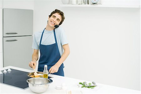 simsearch:695-03378625,k - Young man cooking in kitchen, using cell phone Foto de stock - Royalty Free Premium, Número: 695-05767950