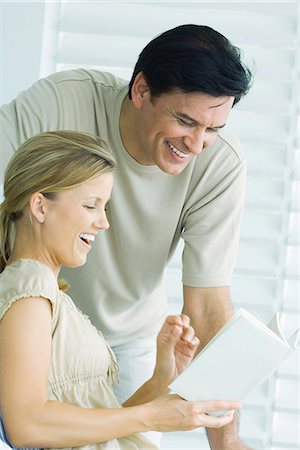 Livre de lecture couple ensemble, homme regarder par-dessus l'épaule de la femme, les deux souriant Photographie de stock - Premium Libres de Droits, Code: 695-05767996