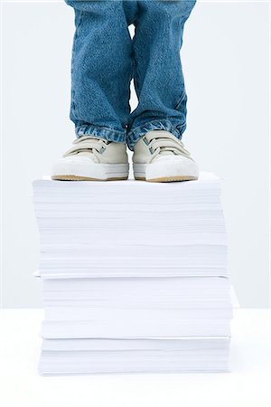 Child standing on tall stack of papers, low angle view, cropped Foto de stock - Sin royalties Premium, Código: 695-05768024