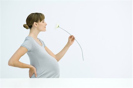 fertilità - Pregnant woman smelling flower, smiling, side view Fotografie stock - Premium Royalty-Free, Codice: 695-05768034