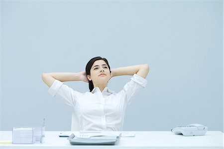 Junge Frau mit den Händen hinter dem Kopf am Schreibtisch sitzen, Wegsehen, Lächeln Stockbilder - Premium RF Lizenzfrei, Bildnummer: 695-05768043