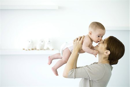 diapering mother to baby - Maman bébé tenue jusqu'à visage souriant, vue latérale Photographie de stock - Premium Libres de Droits, Code: 695-05768072