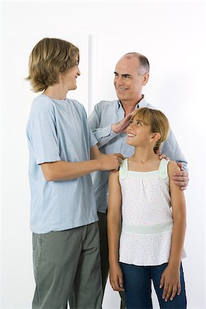 Father standing with teen son and preteen daughter, all smiling at each other Stock Photo - Premium Royalty-Free, Code: 695-05768086
