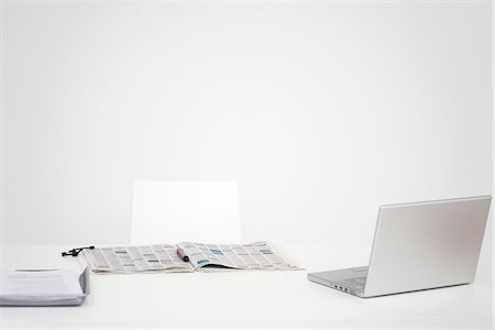 Desk with laptop computer and open newspaper with circled listings Stock Photo - Premium Royalty-Free, Code: 695-05768105