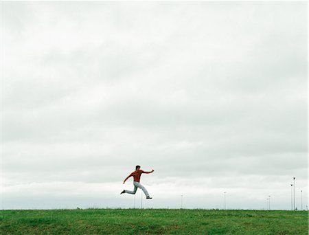 Man jumping on grassy field, in the distance Foto de stock - Sin royalties Premium, Código: 695-05768117