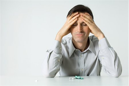 Homme assis à côté de pilules, tête de Holding, des yeux fermés Photographie de stock - Premium Libres de Droits, Code: 695-05768154