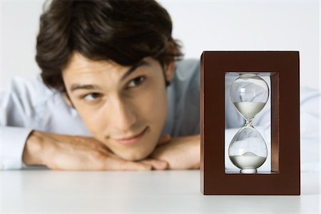 Man looking at hourglass, head resting on hands Stock Photo - Premium Royalty-Free, Code: 695-05768153