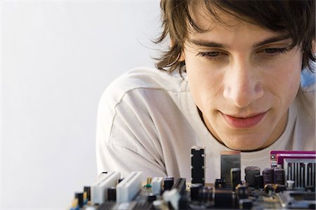 Young man looking down at computer motherboard, close-up Stock Photo - Premium Royalty-Free, Code: 695-05768160