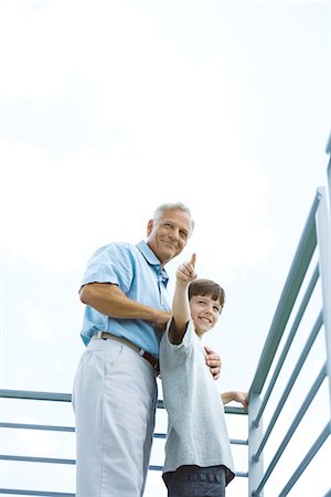 Grandfather and grandson standing on balcony, boy pointing, both looking away Stock Photo - Premium Royalty-Free, Code: 695-05768184