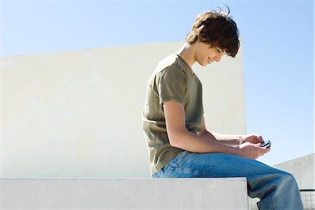 dangling teenage - Teen boy playing handheld video game outdoors Stock Photo - Premium Royalty-Free, Code: 695-05768220