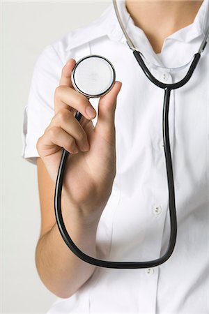 Doctor holding stethoscope and showing it to camera, cropped view Stock Photo - Premium Royalty-Free, Code: 695-05768468