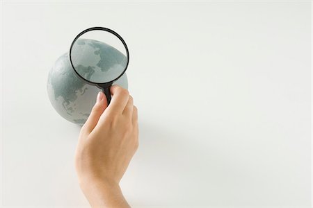 Hand holding magnifying glass over globe, cropped view Foto de stock - Sin royalties Premium, Código: 695-05768469