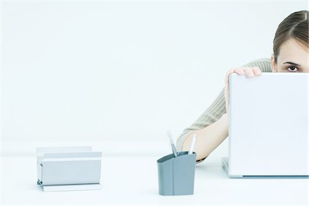 person and lap top and cut out - Young woman peeking over laptop, cropped view Stock Photo - Premium Royalty-Free, Code: 695-05768460