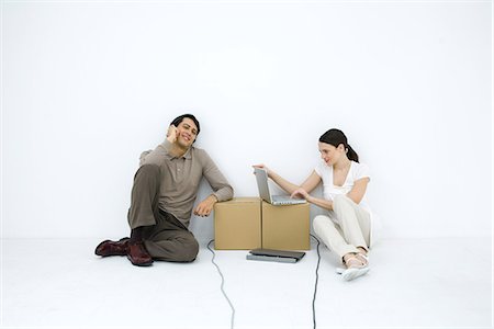 front and centre - Man talking on phone, sitting on floor next to woman using laptop computer at cardboard box desk Stock Photo - Premium Royalty-Free, Code: 695-05768508