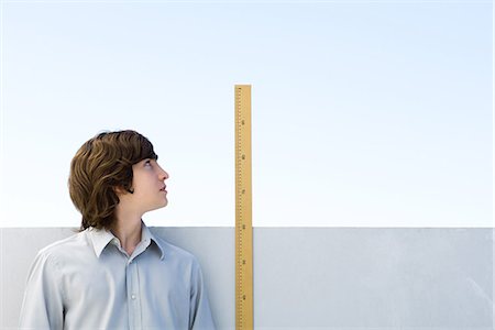 Young man measuring his height with ruler Stock Photo - Premium Royalty-Free, Code: 695-05768535