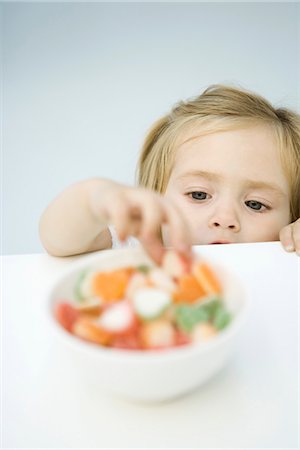 Toddler girl reaching for bowl of candy Stock Photo - Premium Royalty-Free, Code: 695-05768538