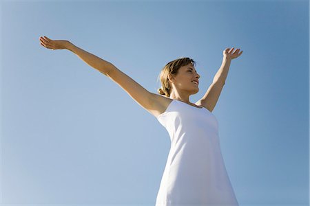 people fresh air - Woman standing outdoors with arms raised, smiling, low angle view Stock Photo - Premium Royalty-Free, Code: 695-05768547